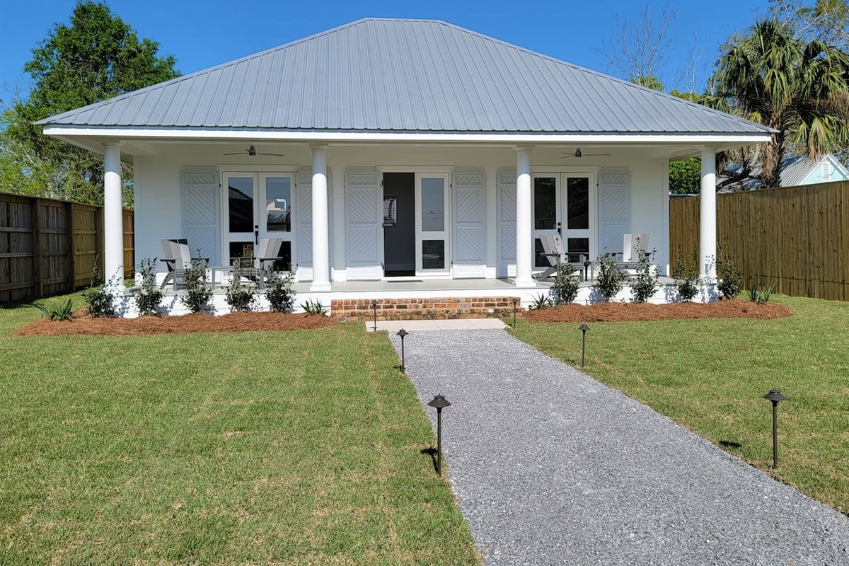 Front view of the house with large porch with comfortable chairs with view of the bay. 