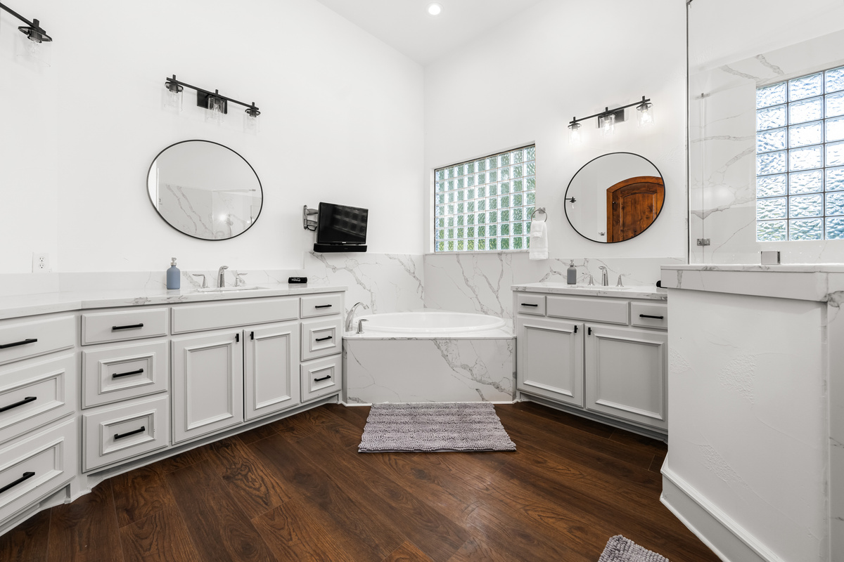 A spacious bathroom featuring dual sinks, a separate soaking tub, and walk-in shower.