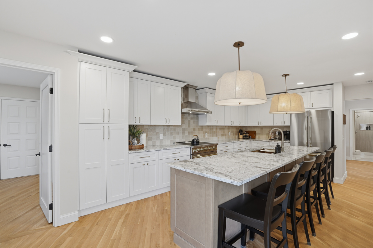 Bright, modern kitchen with a large island, quartz countertops, and bar seating. Clean, open layout with high-end finishes and warm lighting—perfect for cooking, dining, and entertaining.