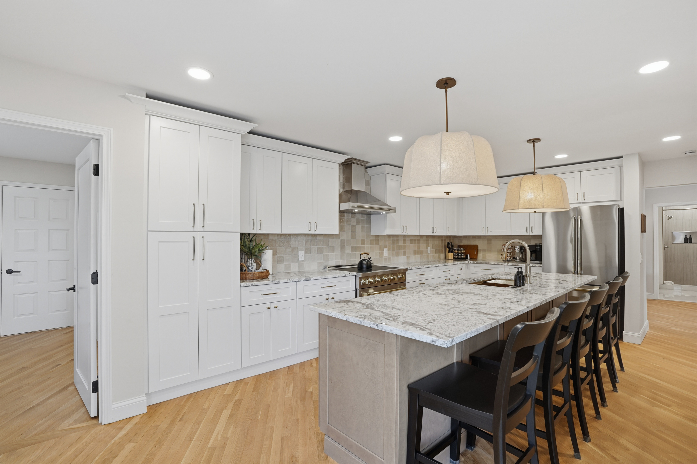 Bright, modern kitchen with a large island, quartz countertops, and bar seating. Clean, open layout with high-end finishes and warm lighting—perfect for cooking, dining, and entertaining.