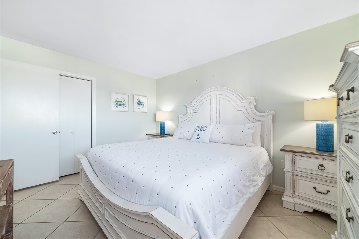 Relax in this bright and airy bedroom, featuring a comfortable bed and subtle coastal accents.
