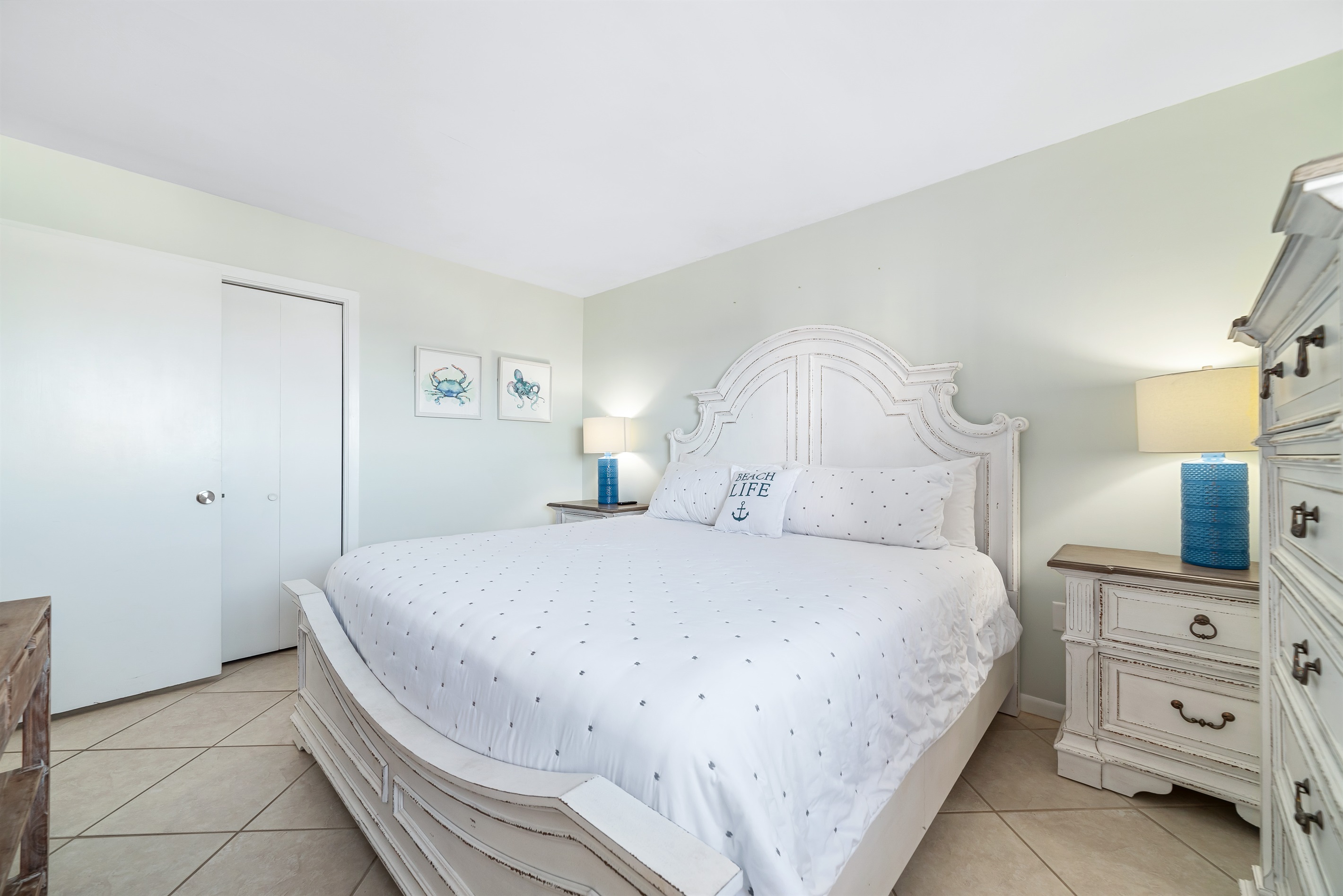 Relax in this bright and airy bedroom, featuring a comfortable bed and subtle coastal accents.