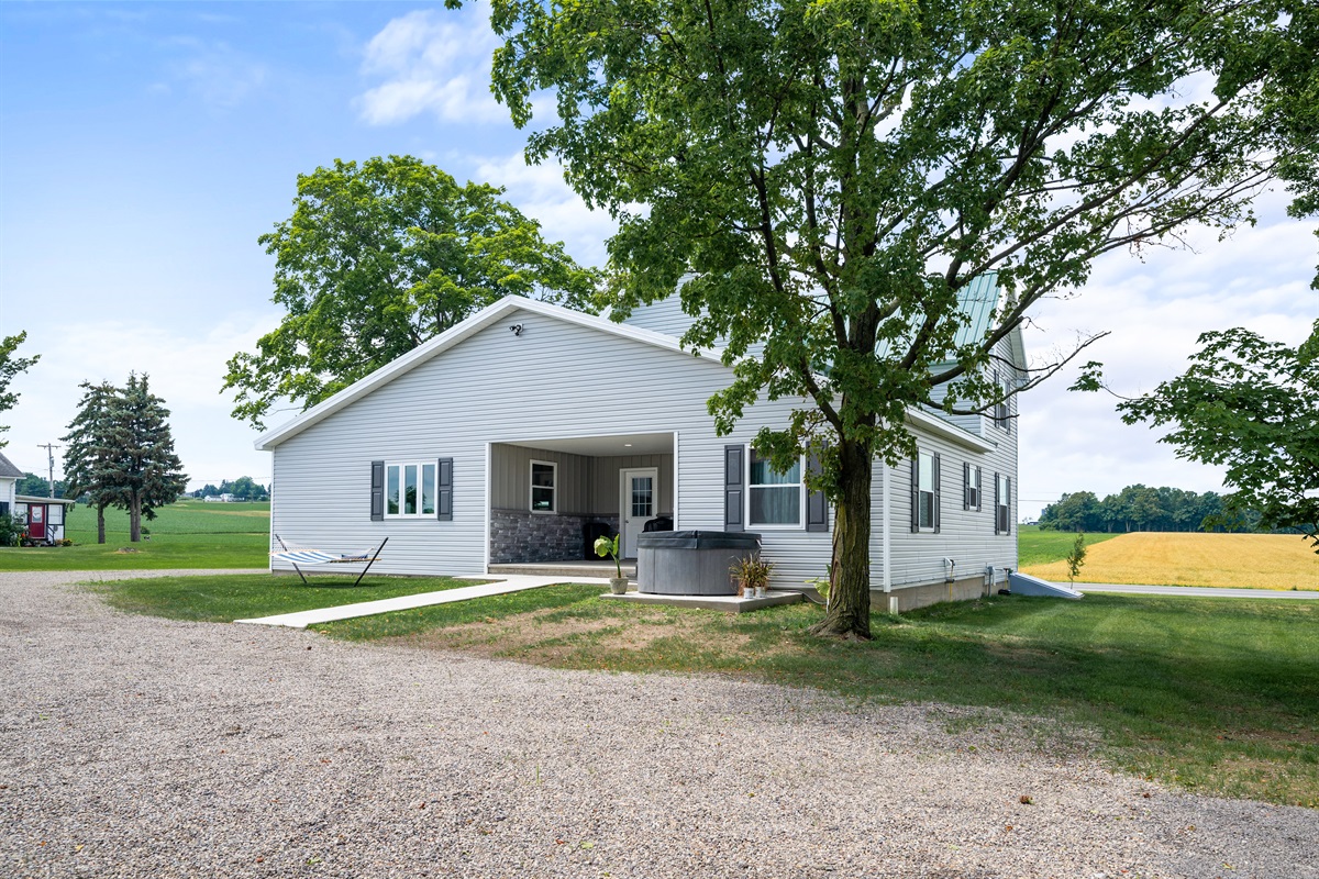 Side view of the home featuring mature trees and a welcoming outdoor hangout area