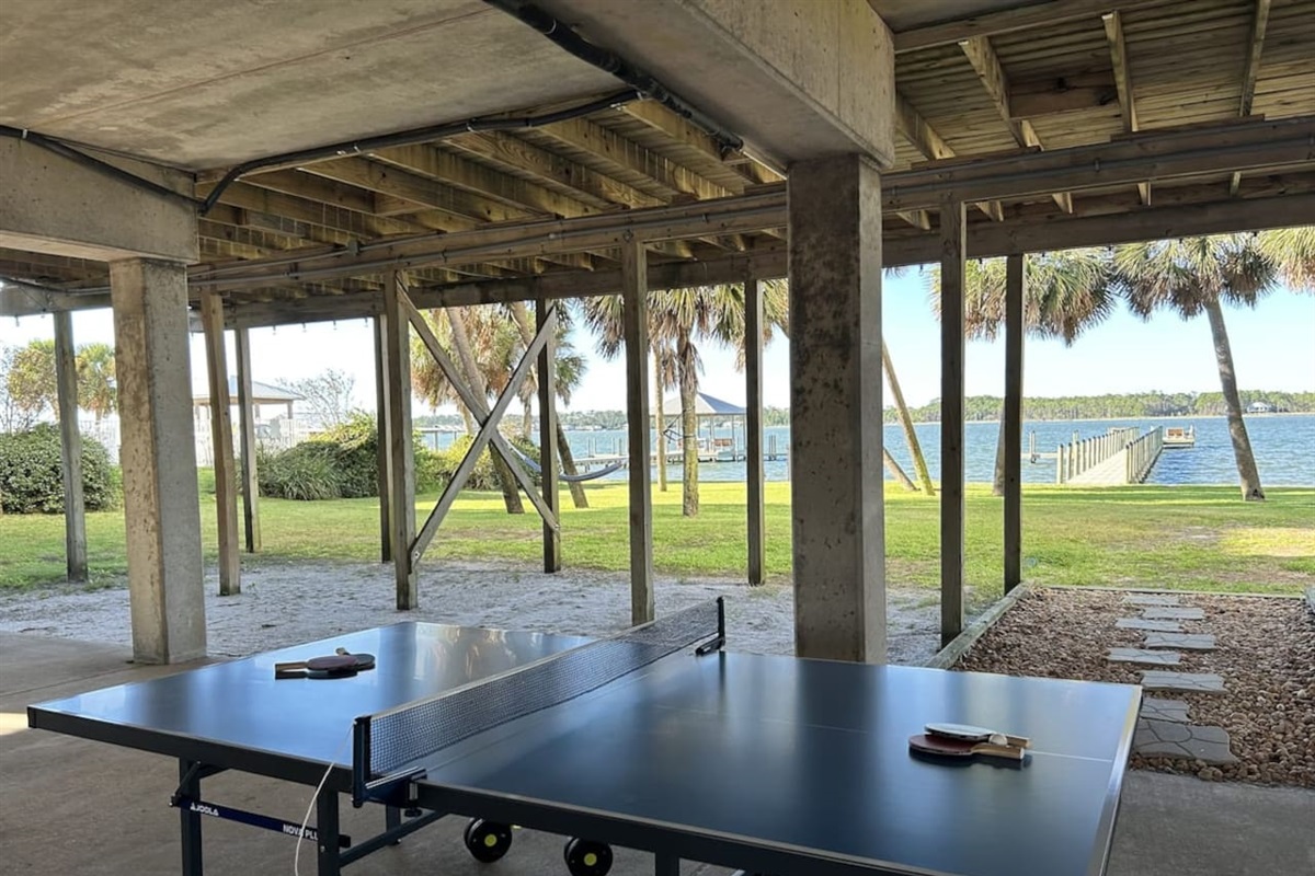 Relaxing lakeside ping pong under a shady patio with serene water views. 