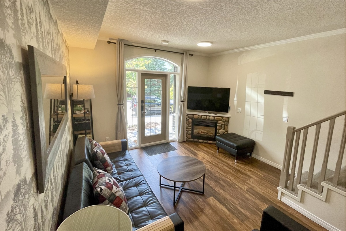 Living room, with your semi-private patio. Frieplace, TV. Stairs to 2nd level visible on the right. Queen Sofabed on the left.