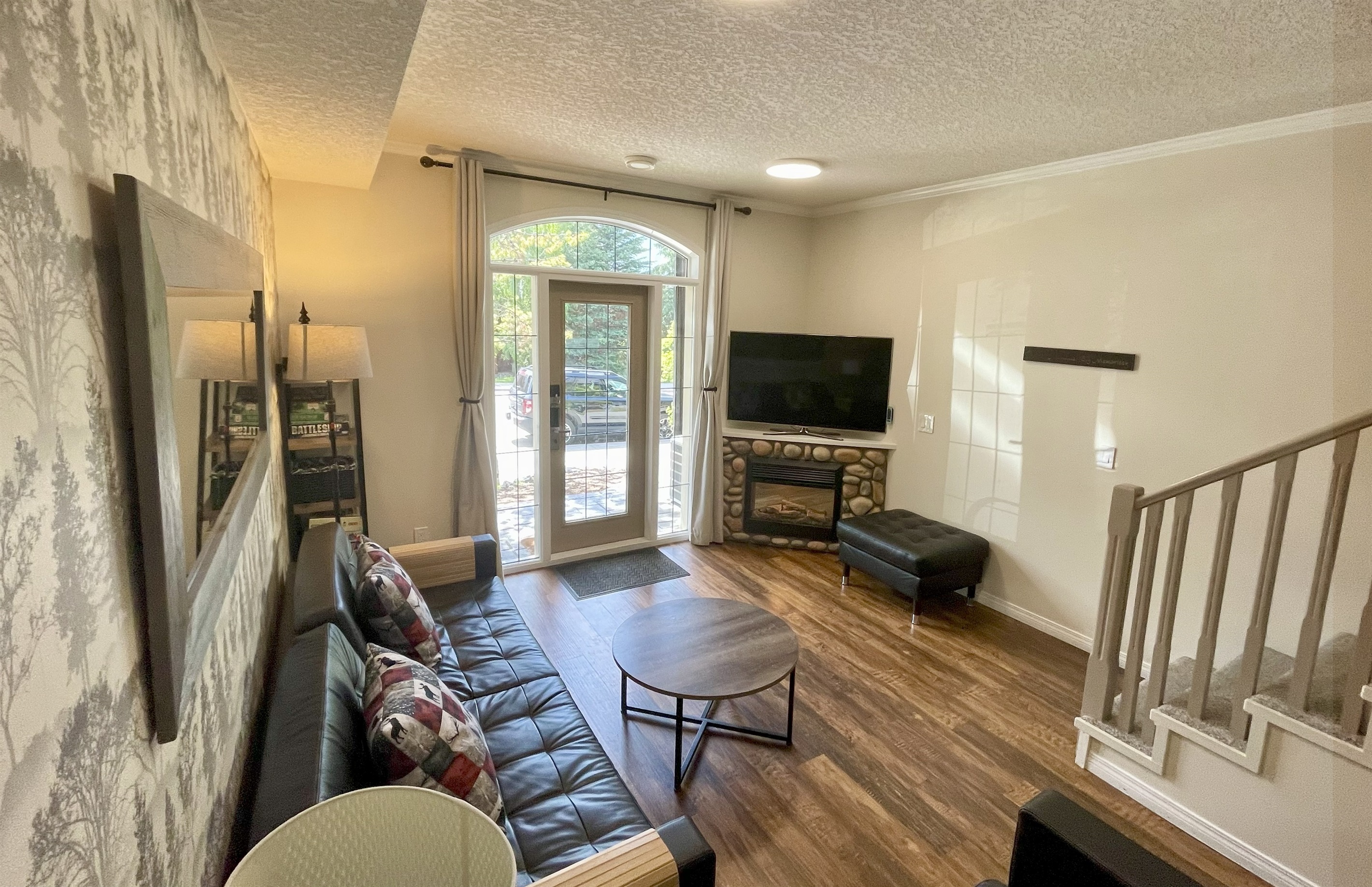 Living room, with your semi-private patio. Frieplace, TV. Stairs to 2nd level visible on the right. Queen Sofabed on the left.