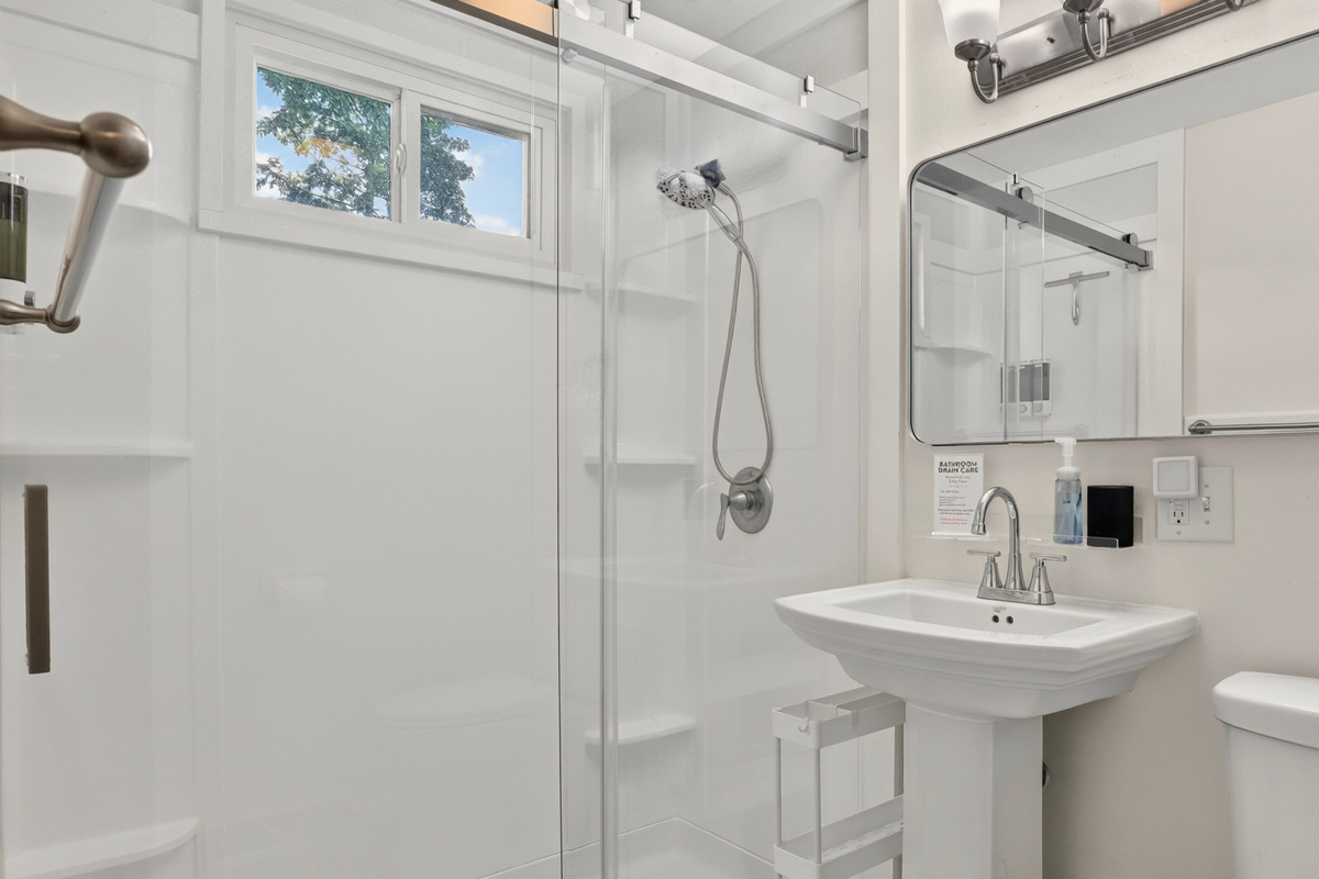 Bright, refreshed bathroom with a walk-in shower, crisp white towels, and a stocked linen closet.