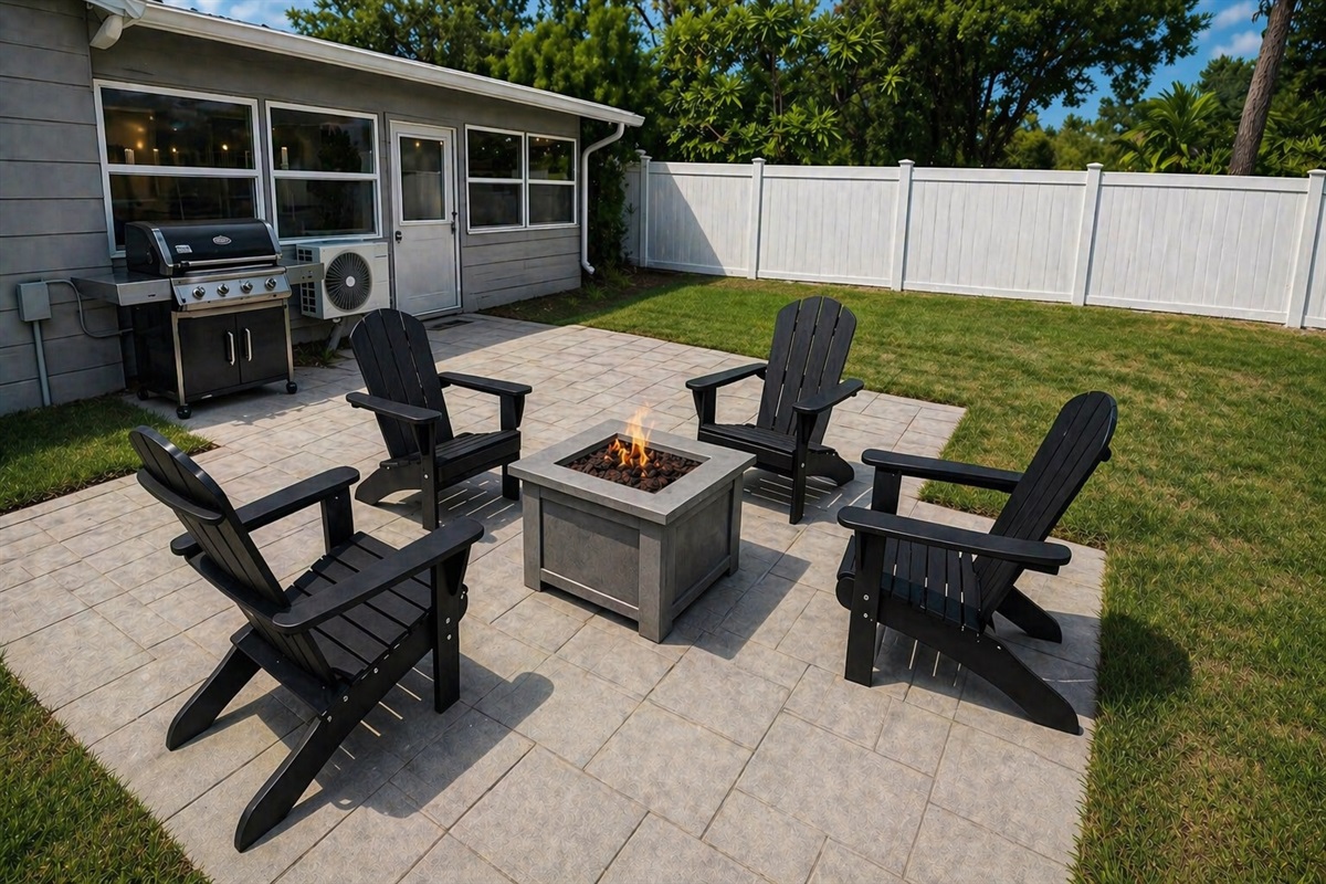 fully fenced backyard with grille, firepit, and loungers