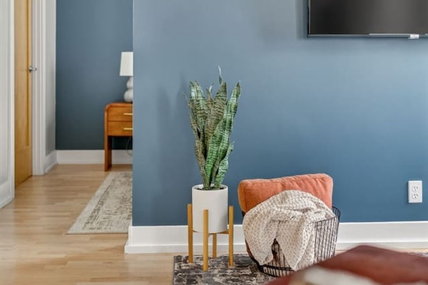 Modern design meets comfort—bold accent walls, greenery, and textured décor create a stylish yet welcoming living space. Kick back, relax, and stream your favorites on the mounted TV.