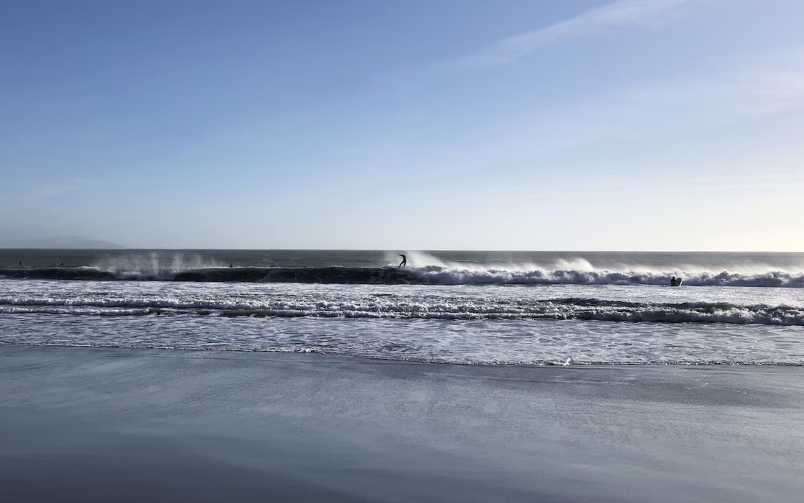 Breaking waves and wet sand under a blue sky