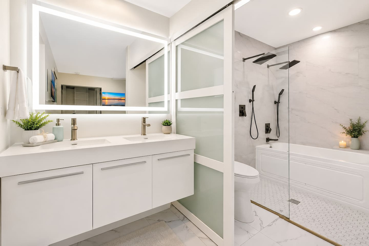 Spa-style full bathroom with a double vanity, illuminated mirror, walk-in rainfall shower and separate soaking tub.