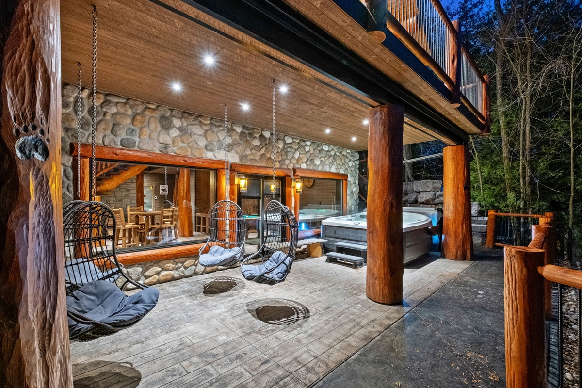Covered lakeside terrace with hanging loungers and private Jacuzzi — perfect in any weather.