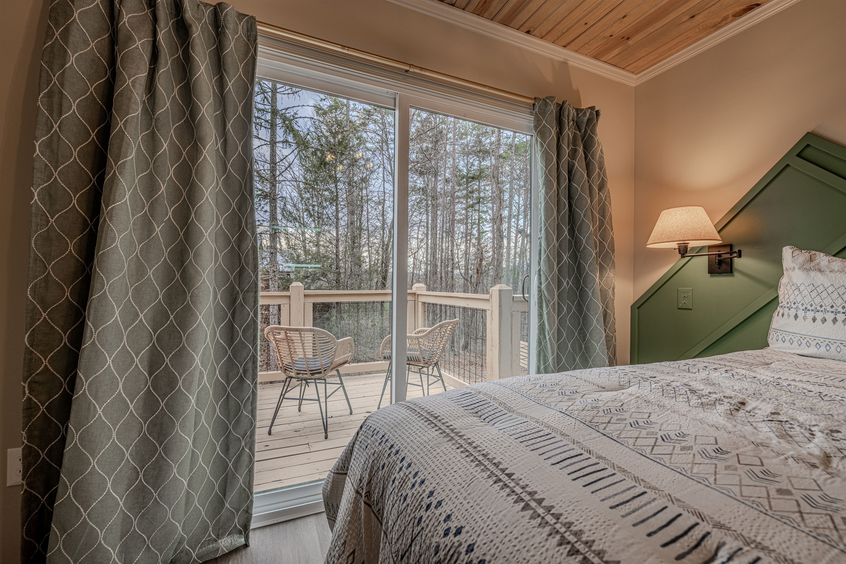 Step out onto your private deck featuring comfortable wicker seating, perfect for enjoying the crisp mountain air and the peaceful view of the trees.