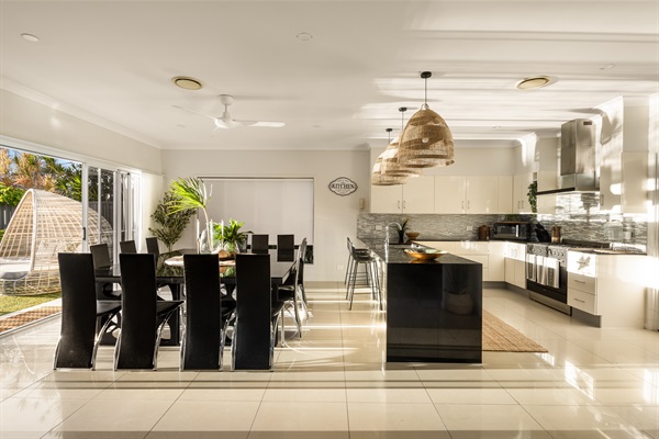 Expansive dining area with seating for large group meals, flowing into the fully equipped kitchen and open-plan living space.