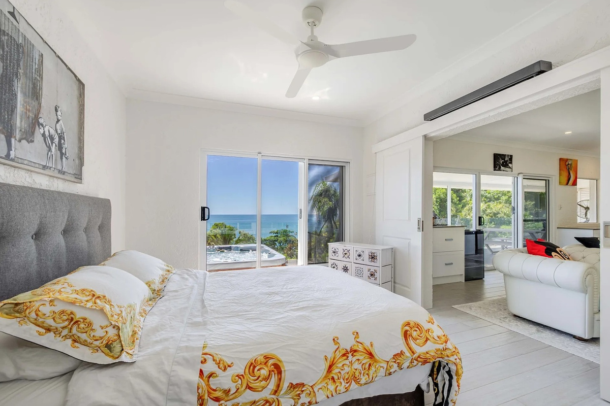 Sliding doors connect the bedroom to the outdoor spa deck, bringing natural light, sea views and easy indoor-outdoor flow.