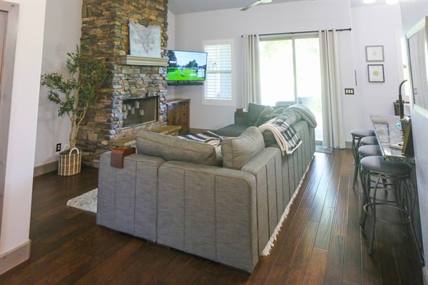LoveSac couch in the great room backing up to the kitchen with direct views of the golf course, smart TV, and stone fireplace with LED candles
