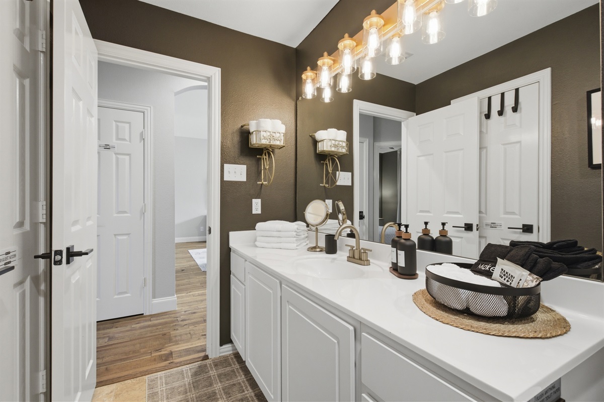 Guest Bathroom Vanity area with mirror, soft lighting, and ample counter space for two. Stocked with essentials by Ginger Lily Farms.
