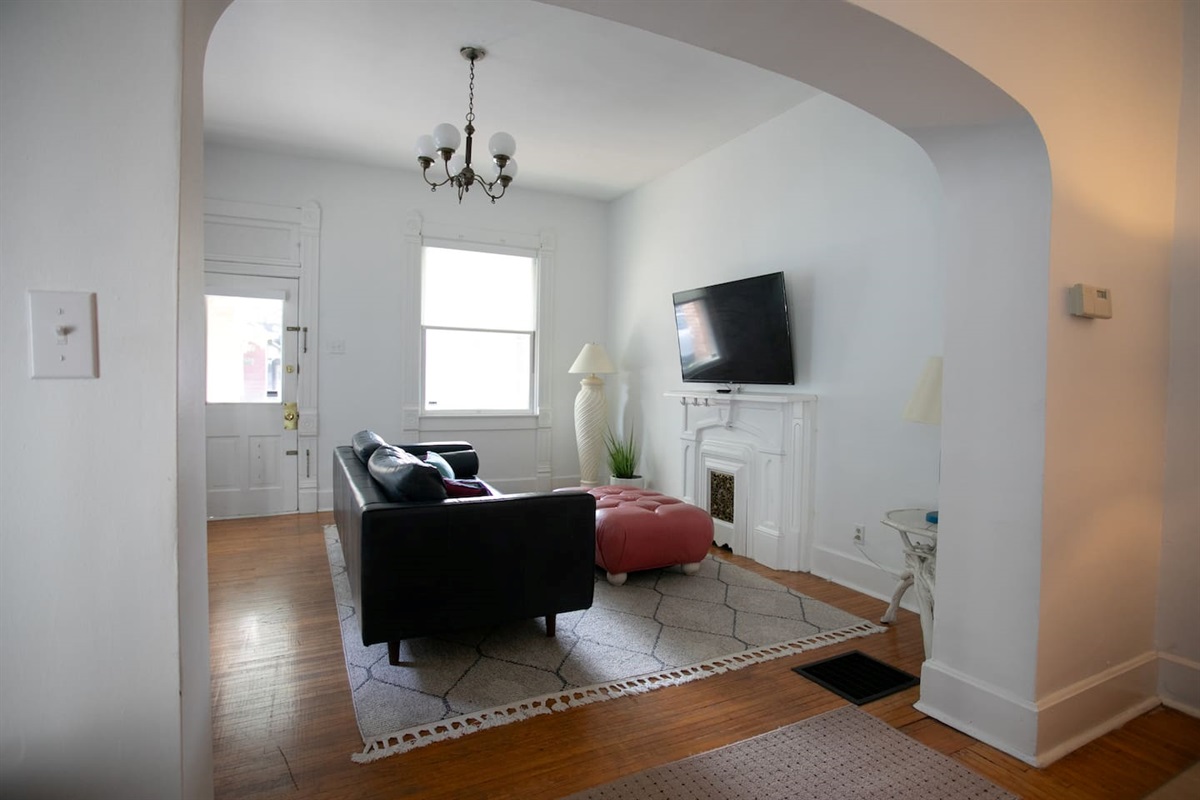 A bright, open view highlighting the room’s scale, natural light, classic arches, and early-1920s charm.