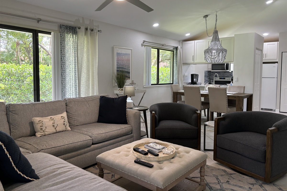 Our large, open living room has seating for six in front of the TV. Two large sliding glass doors let in plenty of light and views of the surrounding, peaceful landscaping.