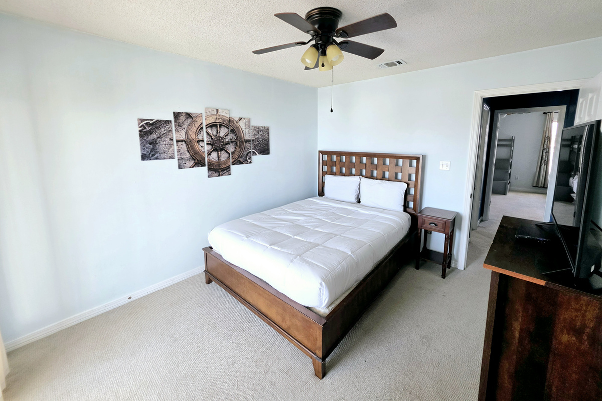 Bedroom with wood headboard and ship's-wheel wall art