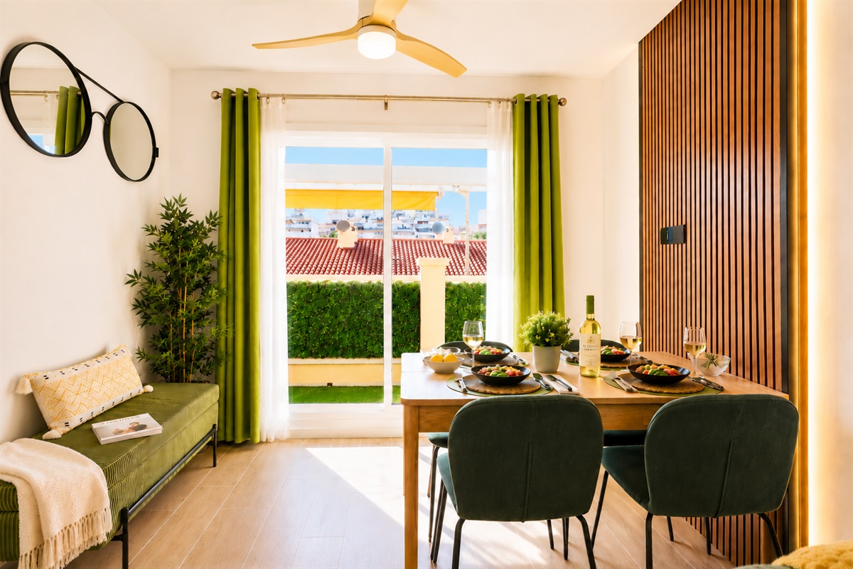 Stylish open-plan living room with a modern kitchen, smart TV, and natural light throughout — ideal for relaxing or sharing a glass of wine after a day by the beach.