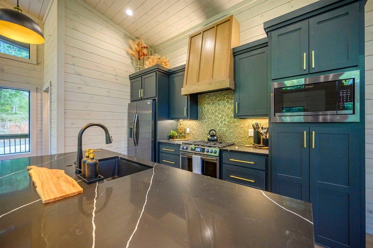 Beautiful black countertops, black stainless appliances and gold hardware are the themed in the Honeycomb Hideout's kitchen.