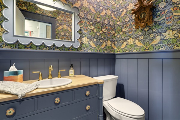 Adorned with William Morris ‘Strawberry Thief’ wallpaper and hand-painted detailing in knobs, cuckoo clock birds and pendant light.