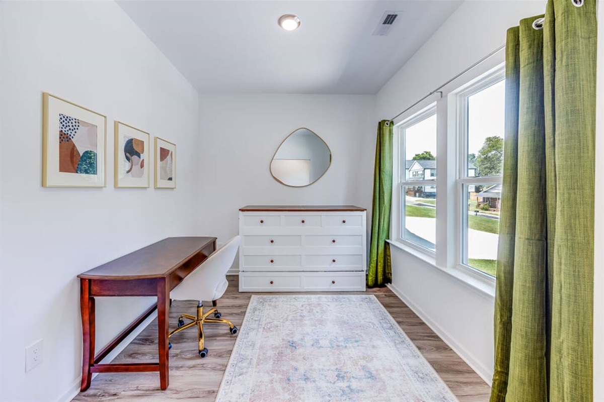 Functional office room with large windows for natural light, featuring a Murphy bed that easily folds out into a comfortable queen bed for extra sleeping space.