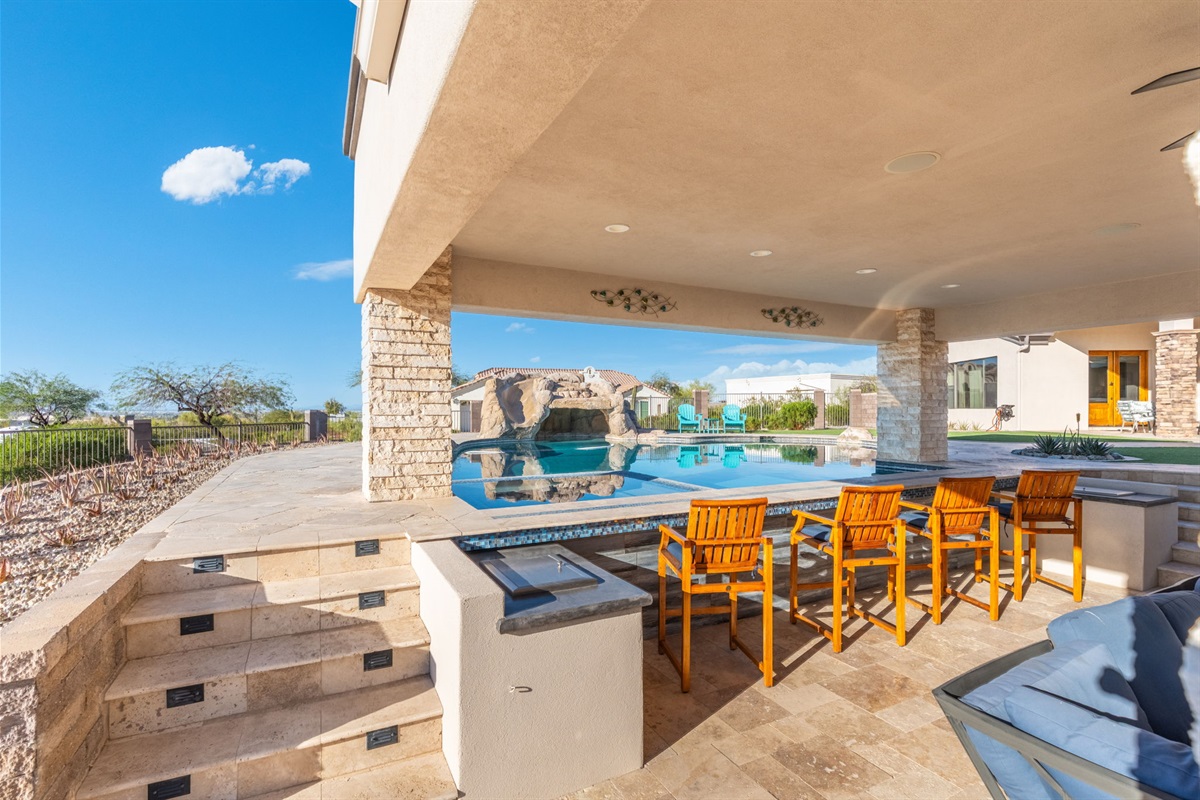 Outdoor kitchen with bar seating beside the pool creates the ultimate space for grilling and socializing together