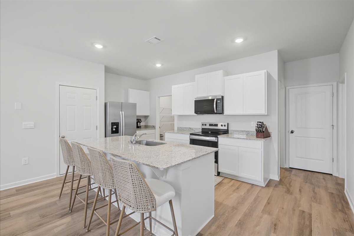Bright white kitchen with granite counters and bar seating for 4