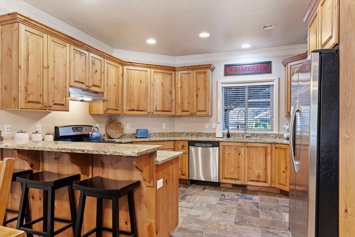 A beautifully appointed kitchen featuring rich wood cabinetry, granite countertops, and bar seating—perfect for both casual and gourmet dining.