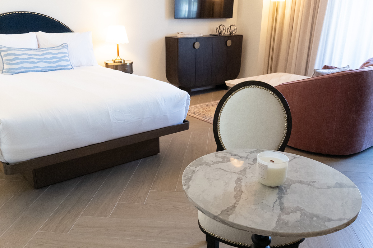 Plush king-size bed dressed in hotel-quality linens, paired with a chic sitting chair.