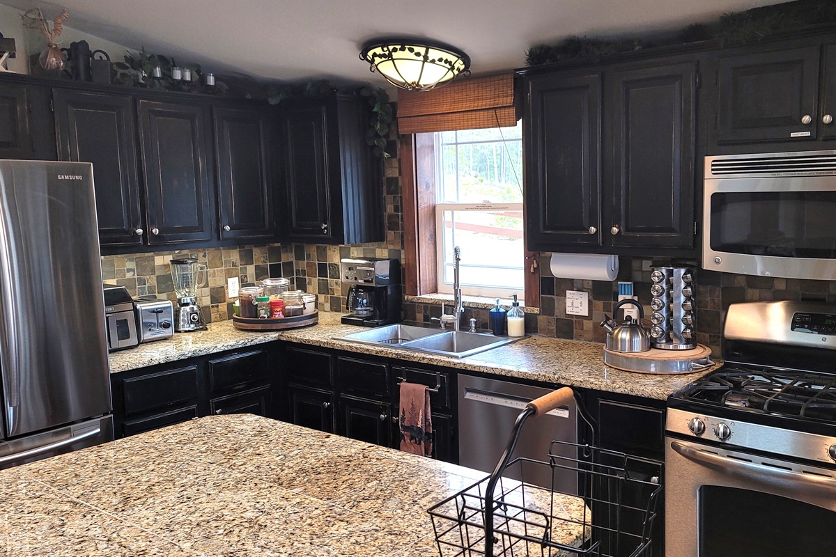 Full kitchen with Island, Airfryer, toaster, blender, standard coffee maker with reusable gold filter, dishwasher, gas stove/oven, double stainless steel sink, assortment of spices, coffee, sugar, creamer, teas provided