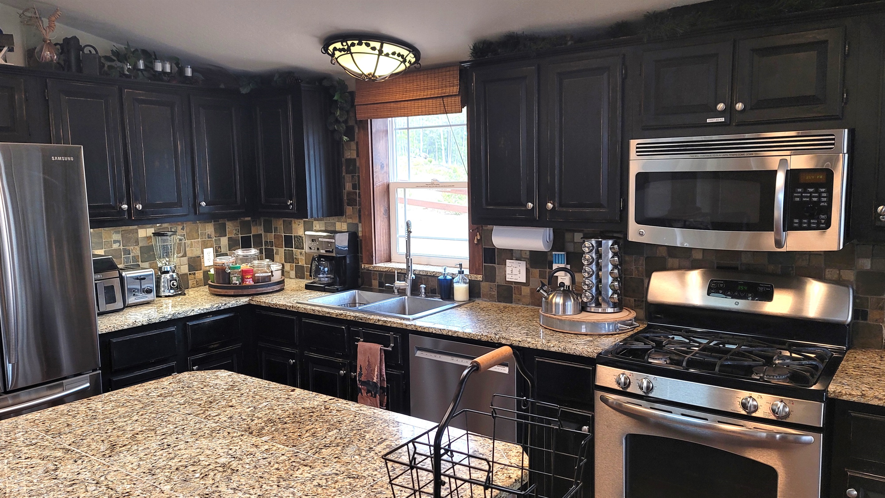 Full kitchen with Island, Airfryer, toaster, blender, standard coffee maker with reusable gold filter, dishwasher, gas stove/oven, double stainless steel sink, assortment of spices, coffee, sugar, creamer, teas provided