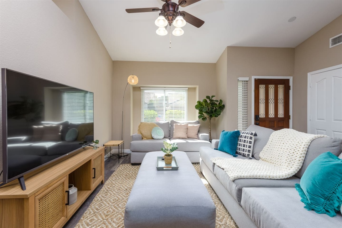 Living room with vaulted ceiling, large Smart TV, comfortable sectional seating, and room to relax or gather indoors.