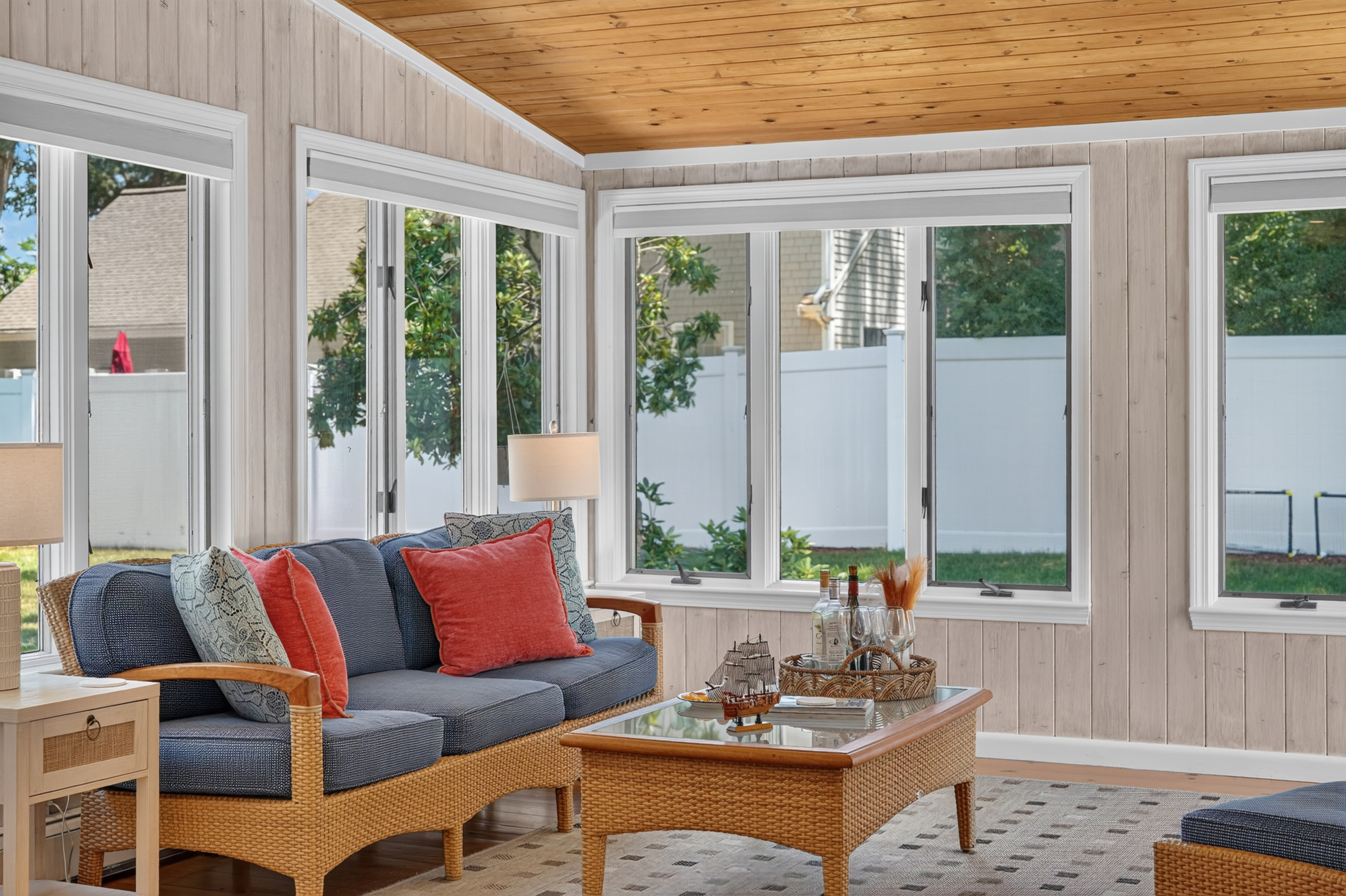 Wall-to-wall windows bring natural light into this inviting sunroom retreat.