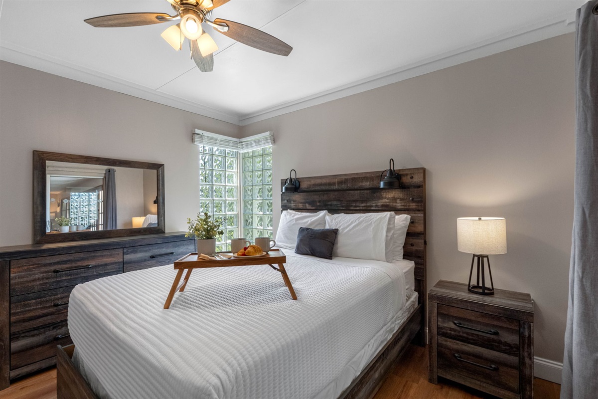 The natural wood furniture and headboard add a rustic charm, while modern touches create a balanced and stylish look.
