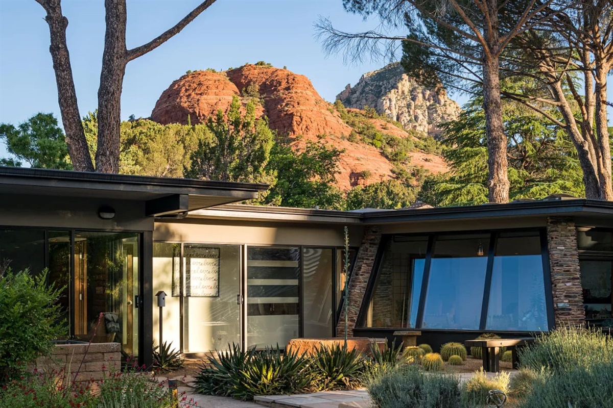 Sunlit exterior highlighting clean mid-century lines, large picture windows, and stunning red rock scenery.