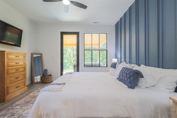 Guest bedroom with dresser storage and a forest-facing window.