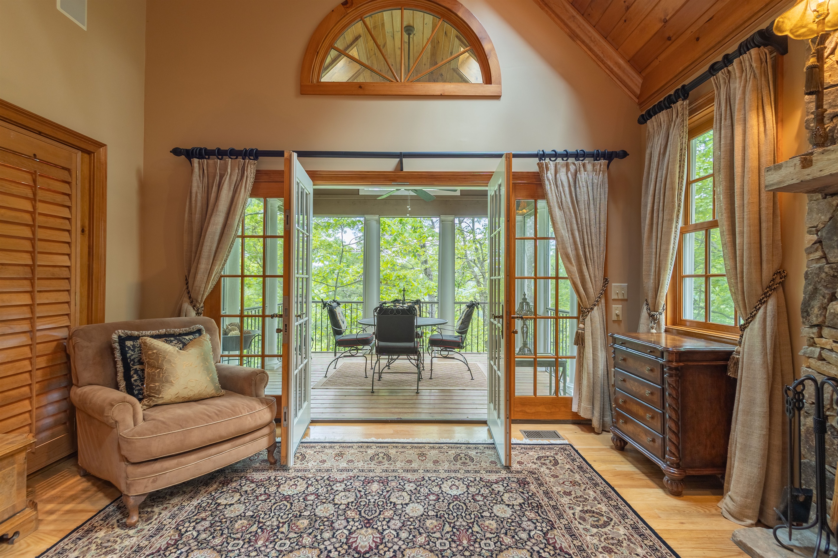 French doors open from the living room to the covered deck, creating an inviting indoor-outdoor space surrounded by the peaceful mountain setting.