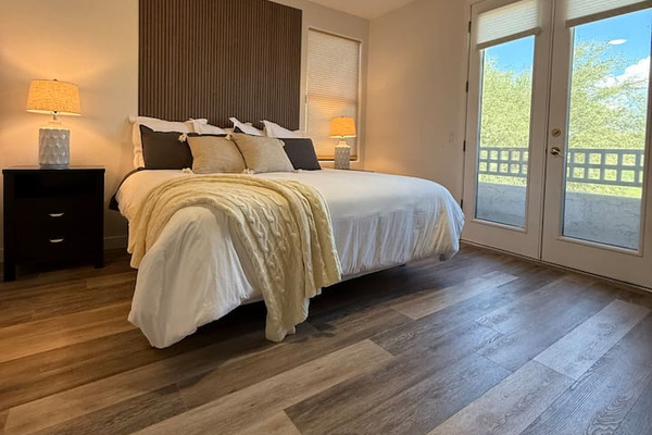 King bedroom with soft layered bedding, bedside lighting, and private balcony access for a comfortable stay.