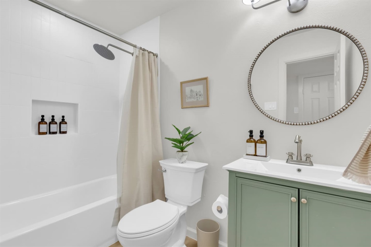 Stylish full bathroom with a bath, rainfall shower, and Ginger Lily Farms shampoo, conditioner, and shower gel. Fresh essentials provided for every stay.