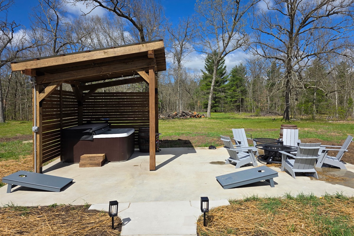 Hot tub patio with firepit and corn hole.