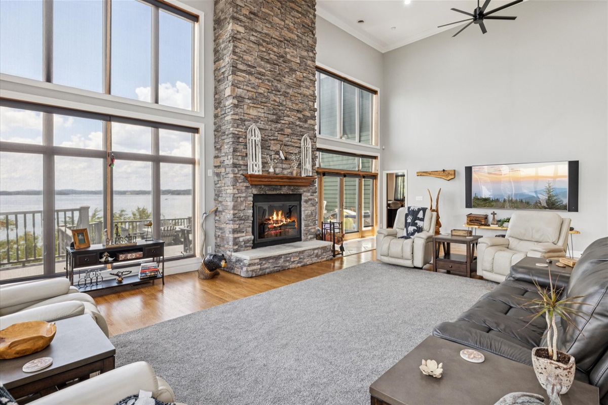Living Room with high ceilings, stone fireplace, large glass walls, large smart TV