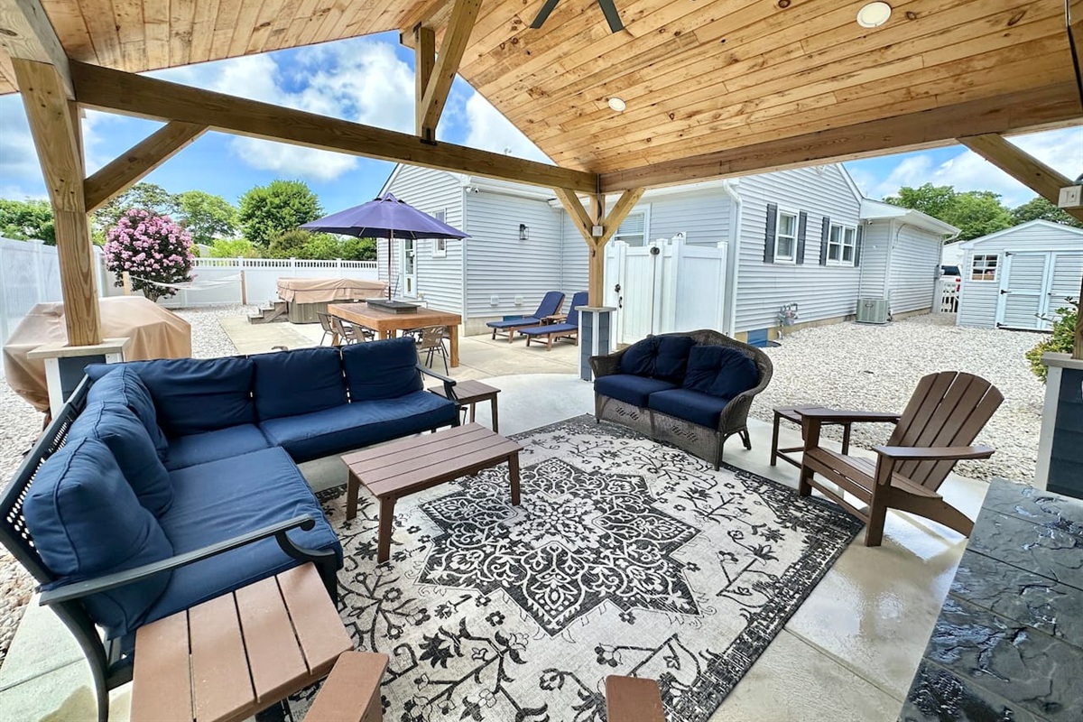 Step into your private outdoor sanctuary! This expansive covered patio features a beautiful wood-planked ceiling, plush navy seating, and a stylish rug—the perfect spot to relax and enjoy the fresh coastal breeze.