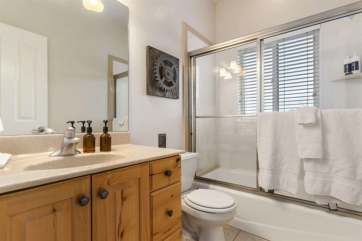 A full bathroom with a tub/shower combination, offering practicality with a polished, comfortable design.