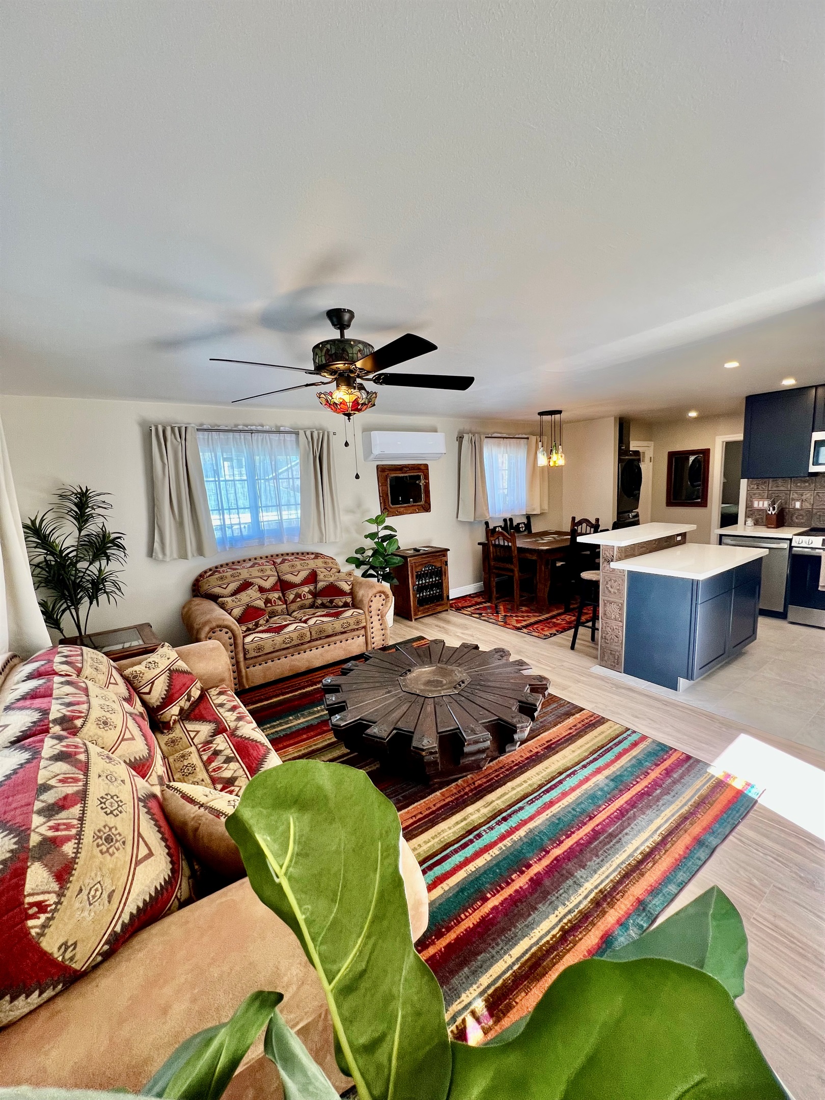 Soak up the natural light in this airy, open-plan space, featuring a unique, rustic Lazy Susan coffee table at the center of the living area.