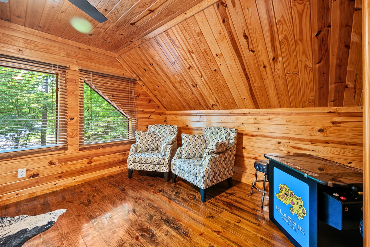 Upstairs loft with reading chairs, game table, and natural light — a great space to unwind or play.