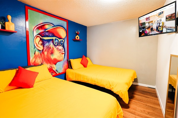 Stylish Slumber: Relax in Comfort with Sunny Yellow Beds, Vibrant Red Accents, and Entertainment at Your Fingertips 🛏️🔵🐒📺