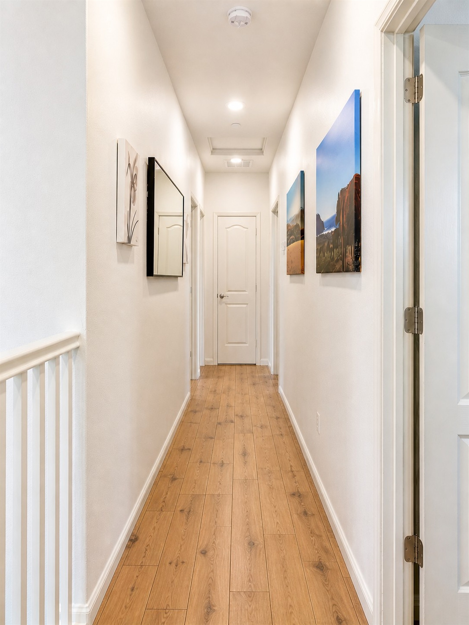 Bright second-floor hallway with natural wood flooring connecting all bedrooms